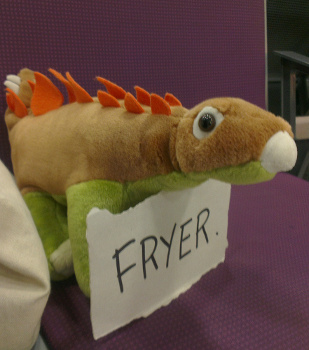 Image of a plush stegosaur holding a carboard sign with "Fryer" written on it.